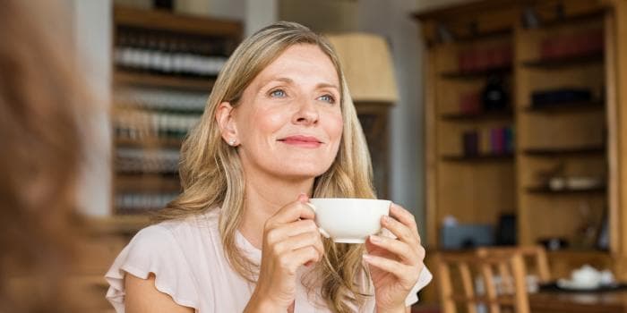 Žena u stolu popíjí kávu s uvolněným výrazem